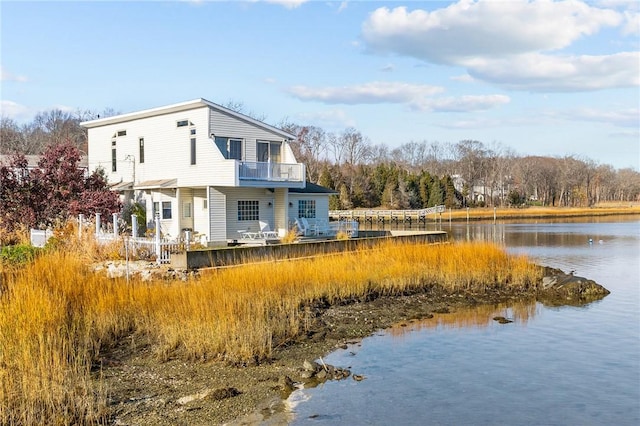 rear view of property featuring a balcony and a water view