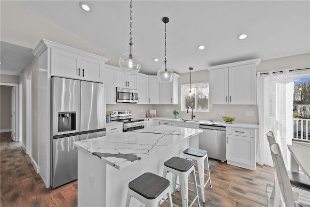 kitchen with decorative light fixtures, a center island, white cabinetry, and stainless steel appliances