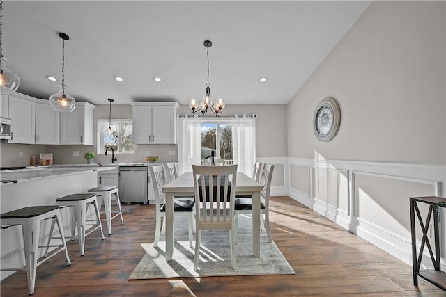 dining room with sink, dark wood-type flooring, and an inviting chandelier