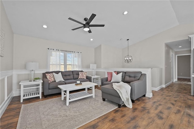 living room with ceiling fan with notable chandelier, dark hardwood / wood-style flooring, and vaulted ceiling