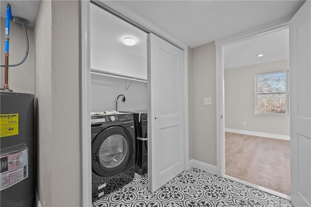 washroom featuring light tile patterned floors, washer / clothes dryer, and water heater