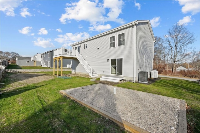 rear view of property with a lawn, a wooden deck, and central AC unit