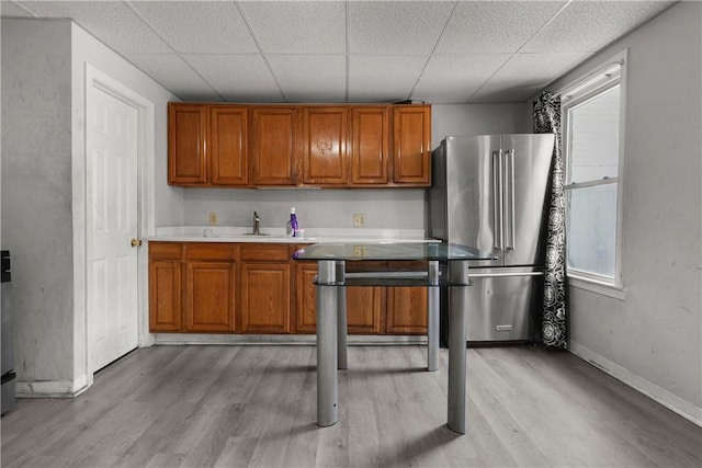 kitchen featuring a wealth of natural light, light wood-type flooring, sink, and high quality fridge