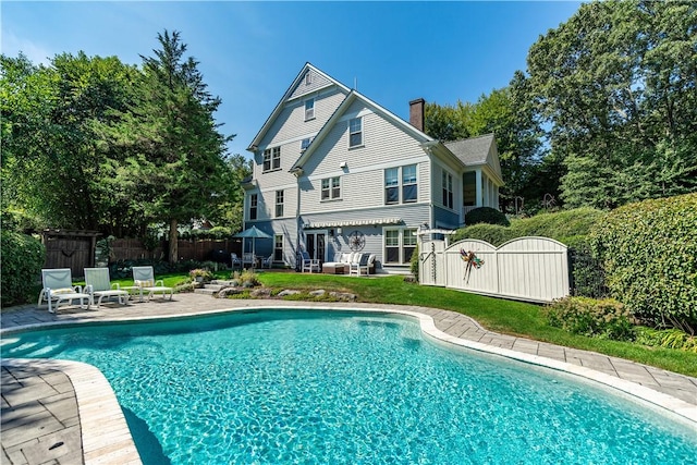 rear view of property with a fenced in pool and a patio