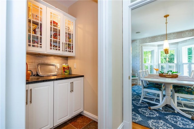 bar with tasteful backsplash, white cabinetry, and pendant lighting