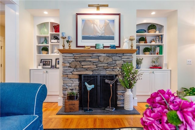 living room with a fireplace, light wood-type flooring, and built in features