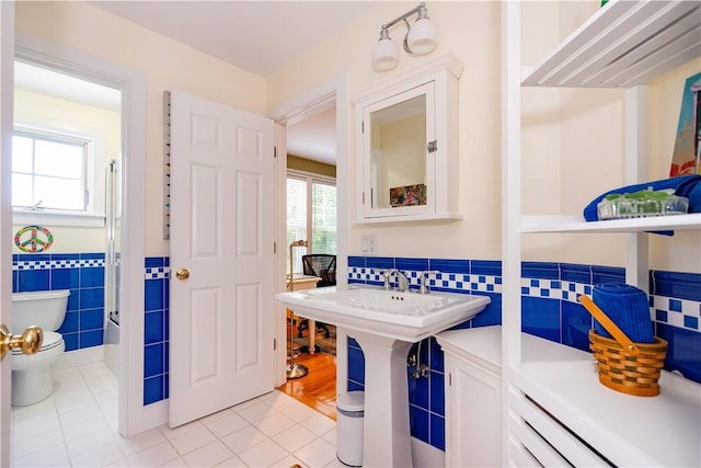 bathroom featuring tile patterned floors, sink, toilet, and tile walls