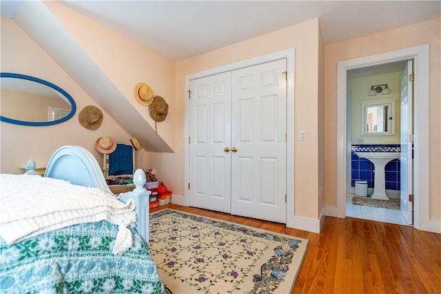 bedroom featuring connected bathroom, a closet, and hardwood / wood-style flooring