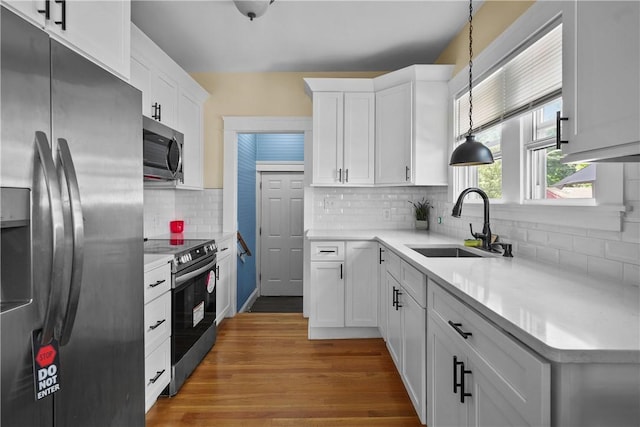 kitchen with stainless steel appliances, white cabinetry, and hanging light fixtures