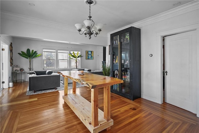 dining room with crown molding, hardwood / wood-style floors, and an inviting chandelier