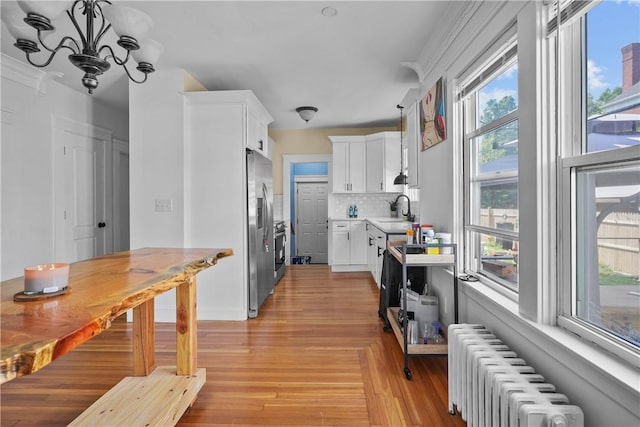 kitchen with backsplash, radiator, sink, stainless steel fridge with ice dispenser, and white cabinetry