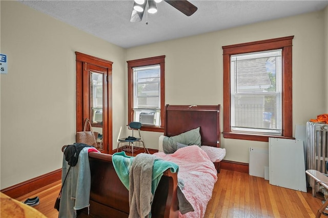 living area featuring radiator heating unit, light wood-type flooring, a textured ceiling, and ceiling fan