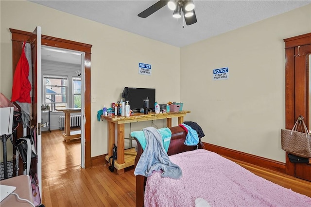 bedroom featuring radiator heating unit, hardwood / wood-style flooring, and ceiling fan