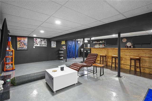 interior space with bar area, wood walls, a drop ceiling, and concrete flooring