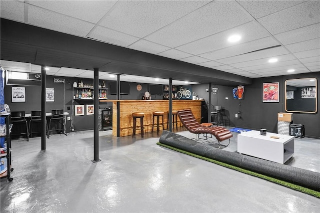 basement featuring indoor bar and a paneled ceiling