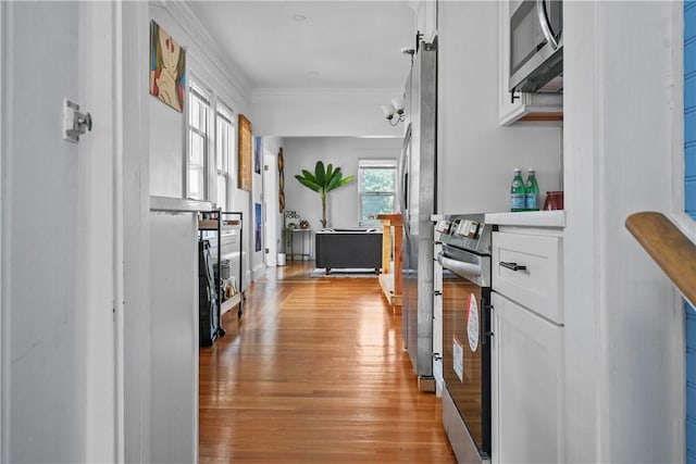 hallway featuring light wood-type flooring and ornamental molding