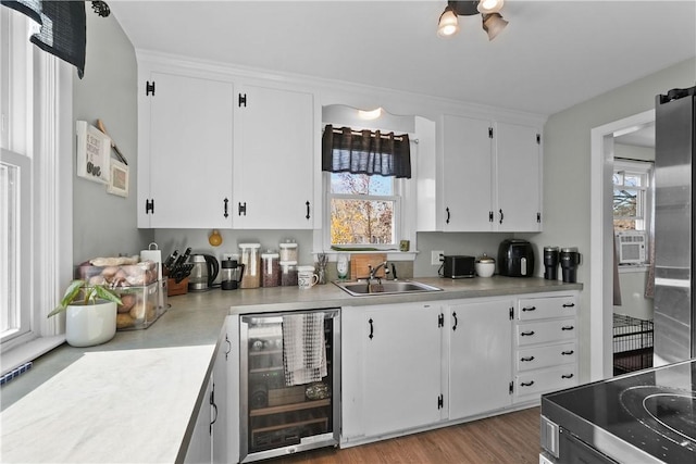 kitchen featuring sink, white cabinets, beverage cooler, and stove