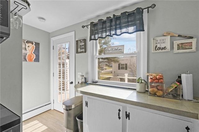 interior space with white cabinets, a baseboard radiator, and light hardwood / wood-style floors