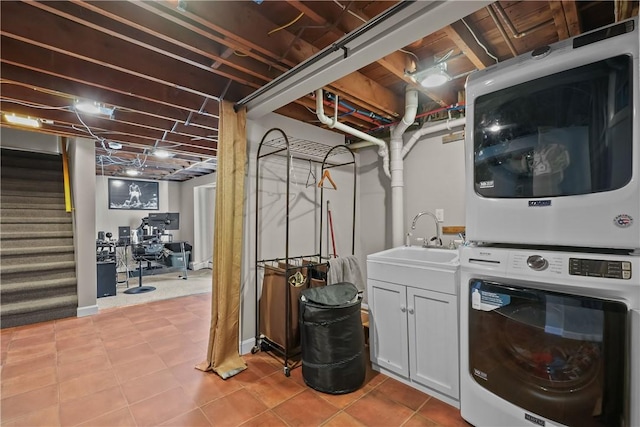 washroom featuring light tile patterned flooring, stacked washer / dryer, cabinets, and sink