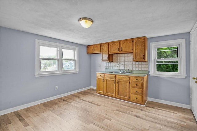 kitchen with decorative backsplash, light hardwood / wood-style floors, plenty of natural light, and sink