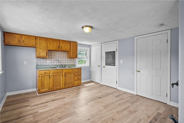 kitchen with decorative backsplash, sink, and light wood-type flooring