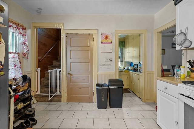 kitchen with white range oven, wood walls, white cabinets, and light tile patterned floors