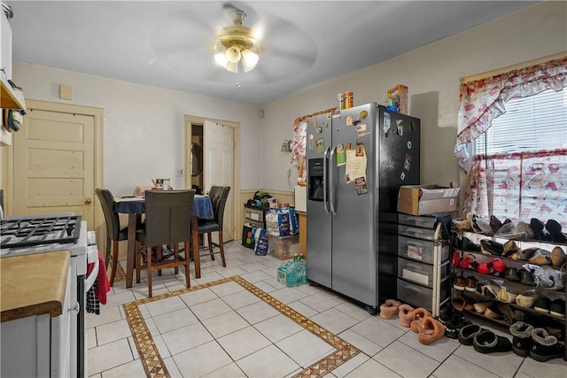 kitchen with white cabinetry, ceiling fan, stainless steel refrigerator with ice dispenser, white range with gas cooktop, and light tile patterned floors