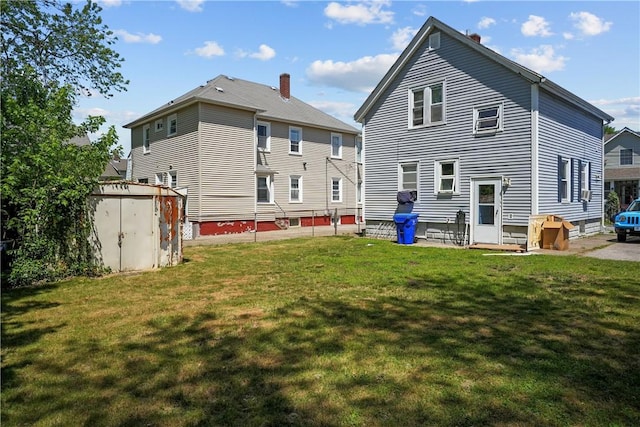 back of house with a lawn and a shed