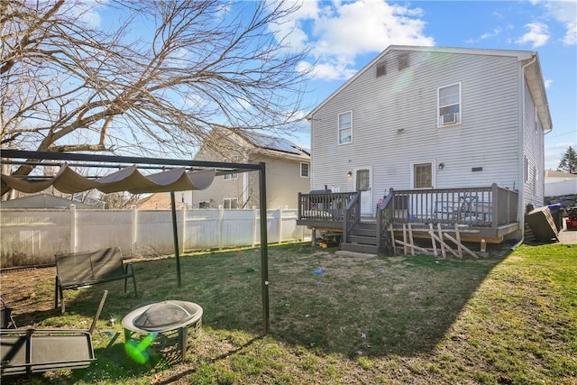 back of property featuring a fire pit, a lawn, and a wooden deck