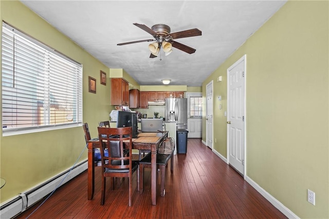 dining area with dark wood-type flooring, a baseboard radiator, ceiling fan, and a healthy amount of sunlight