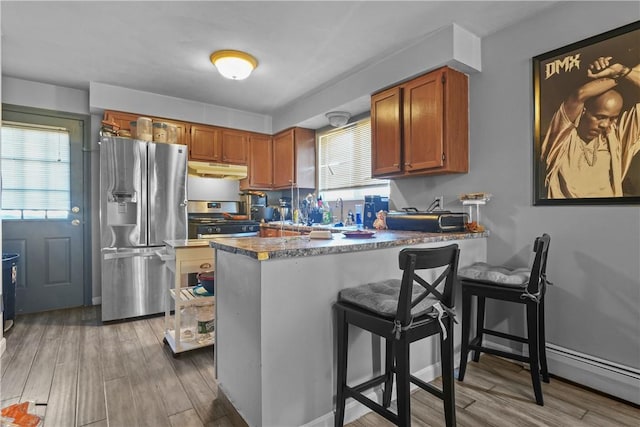 kitchen featuring kitchen peninsula, a kitchen breakfast bar, stainless steel appliances, and light hardwood / wood-style flooring