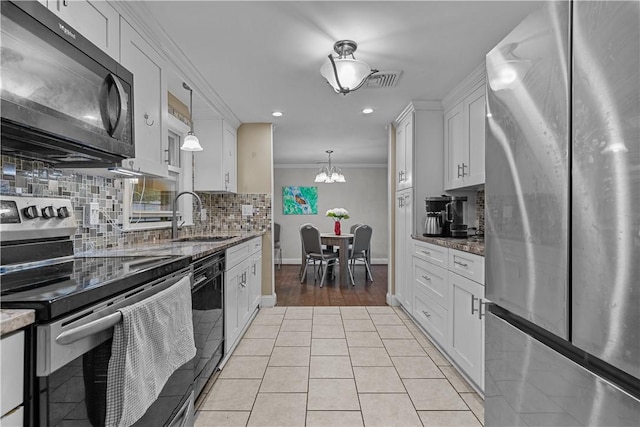 kitchen with dark stone counters, black appliances, white cabinets, crown molding, and hanging light fixtures