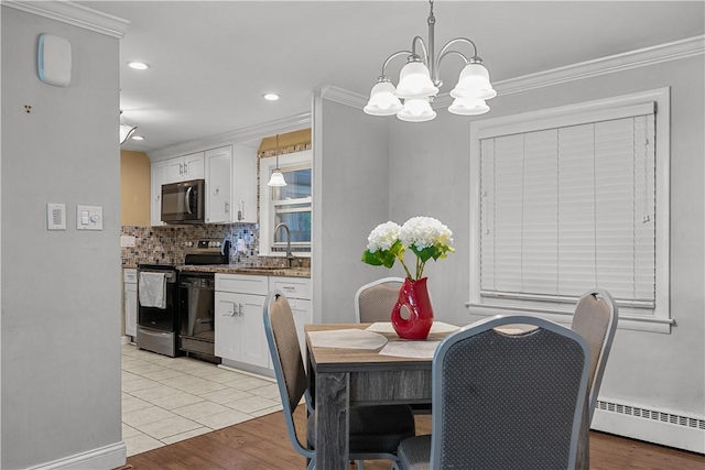 dining area featuring ornamental molding, a baseboard heating unit, sink, light tile patterned floors, and a chandelier