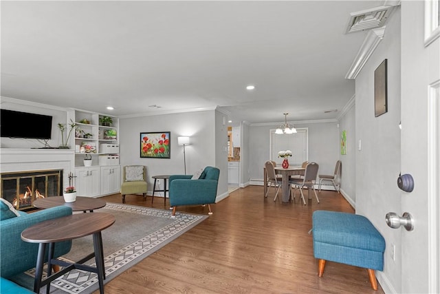 living room featuring hardwood / wood-style flooring, built in features, and ornamental molding