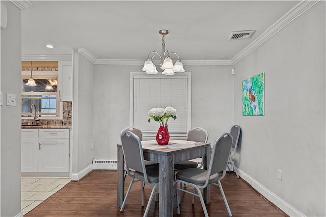 dining area featuring crown molding, a baseboard radiator, hardwood / wood-style flooring, and a notable chandelier