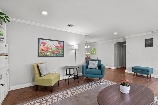 living area with dark wood-type flooring, ornamental molding, and a notable chandelier