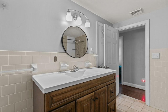 bathroom featuring tile patterned flooring, vanity, and tile walls