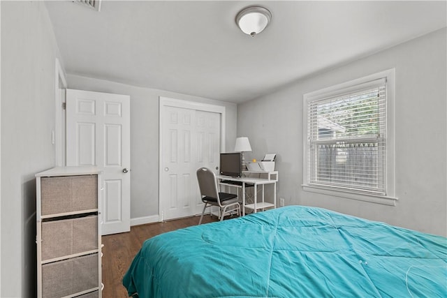 bedroom with dark hardwood / wood-style flooring and a closet