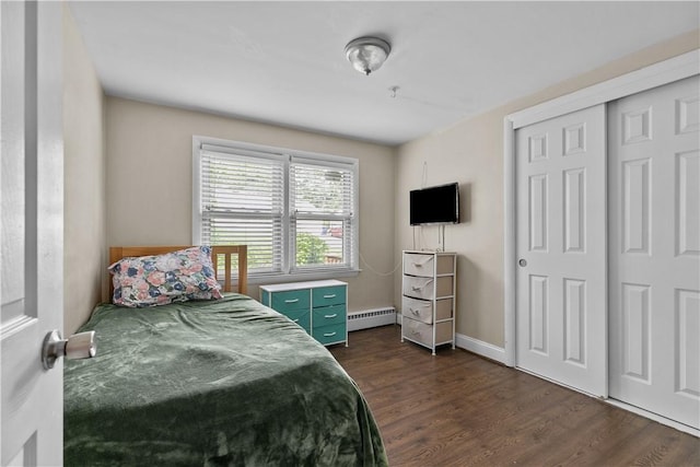 bedroom with dark hardwood / wood-style flooring, a closet, and a baseboard heating unit