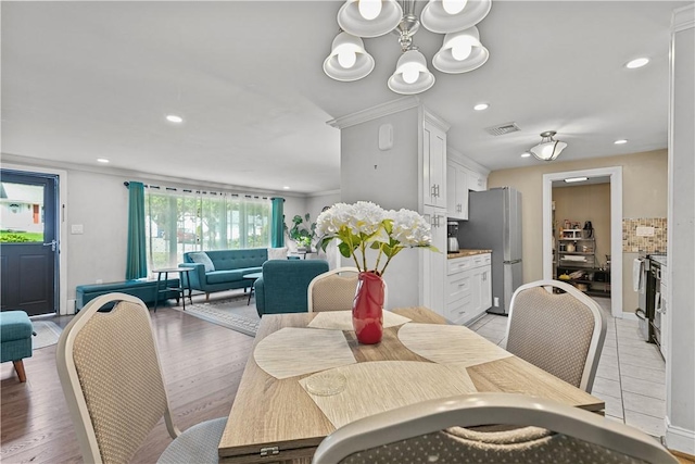 dining area with light hardwood / wood-style floors and ornamental molding