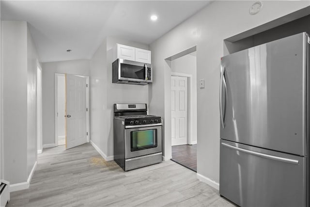 kitchen with white cabinetry, stainless steel appliances, a baseboard heating unit, and light hardwood / wood-style floors