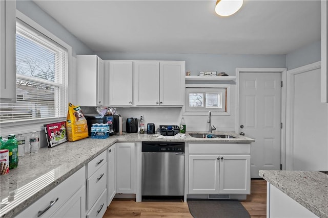 kitchen with white cabinetry, dishwasher, light hardwood / wood-style floors, and sink