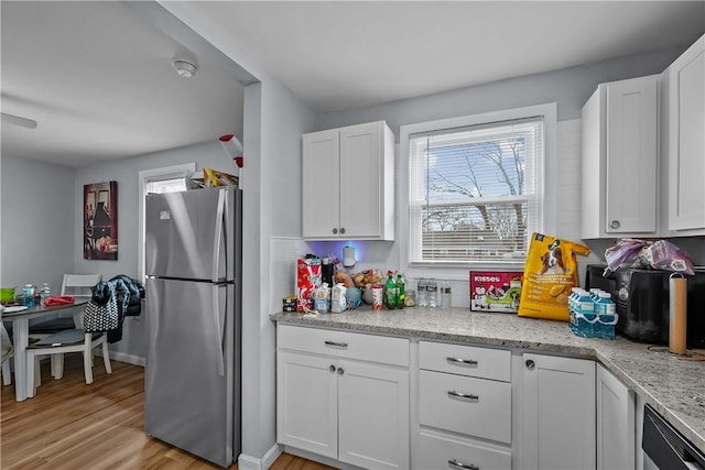 kitchen with decorative backsplash, stainless steel fridge, light wood-type flooring, light stone counters, and white cabinetry