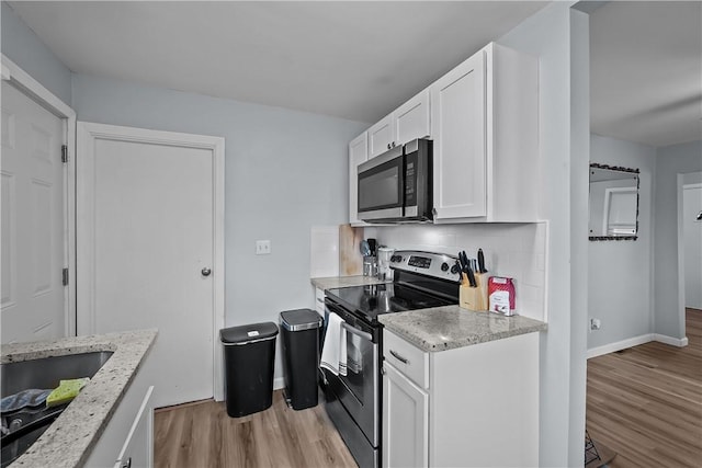 kitchen featuring white cabinets, black electric range, decorative backsplash, light hardwood / wood-style floors, and light stone counters