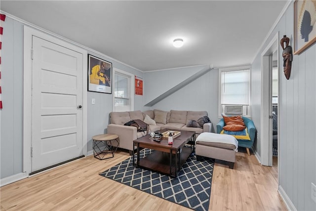 living room featuring light wood-type flooring, wooden walls, cooling unit, and ornamental molding