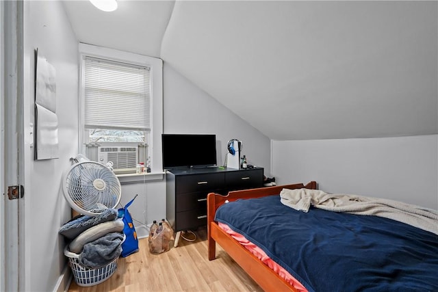 bedroom with cooling unit, light hardwood / wood-style floors, and lofted ceiling