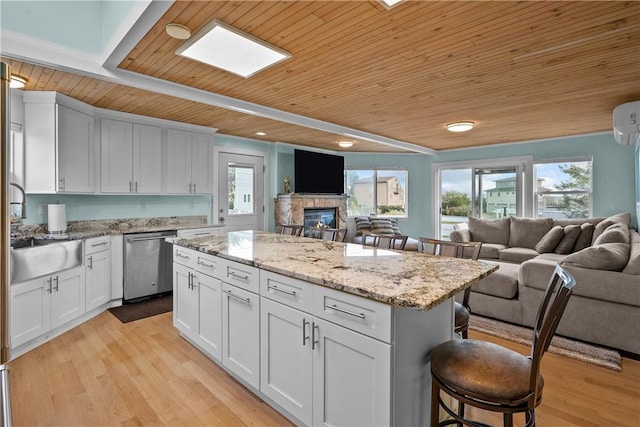 kitchen with a kitchen breakfast bar, white cabinetry, wood ceiling, and stainless steel dishwasher