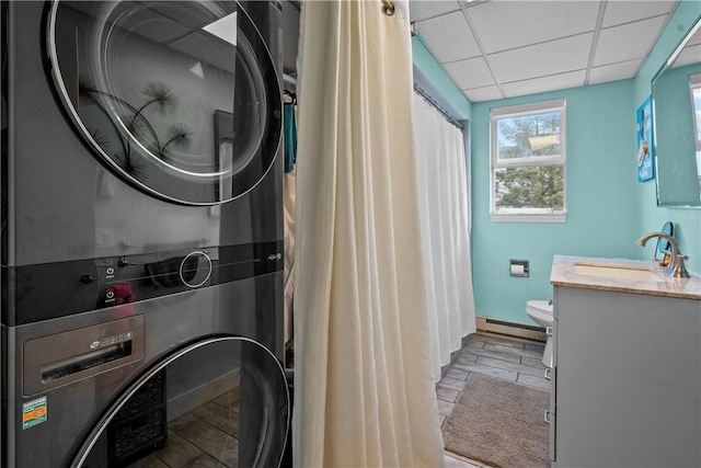 laundry area featuring stacked washing maching and dryer, sink, and a baseboard radiator