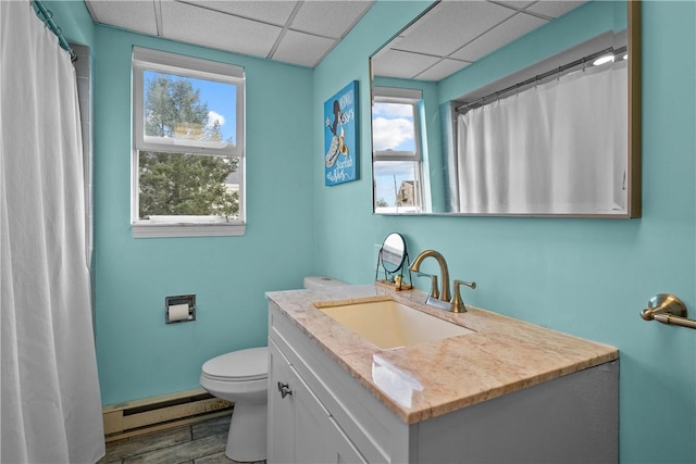 bathroom featuring a paneled ceiling, vanity, toilet, and a baseboard heating unit