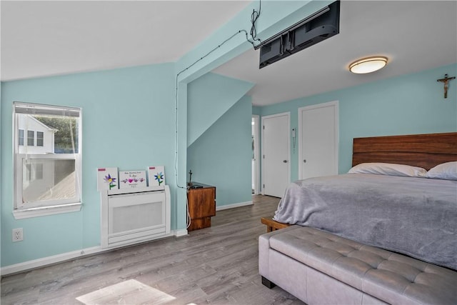 bedroom featuring light wood-type flooring and vaulted ceiling